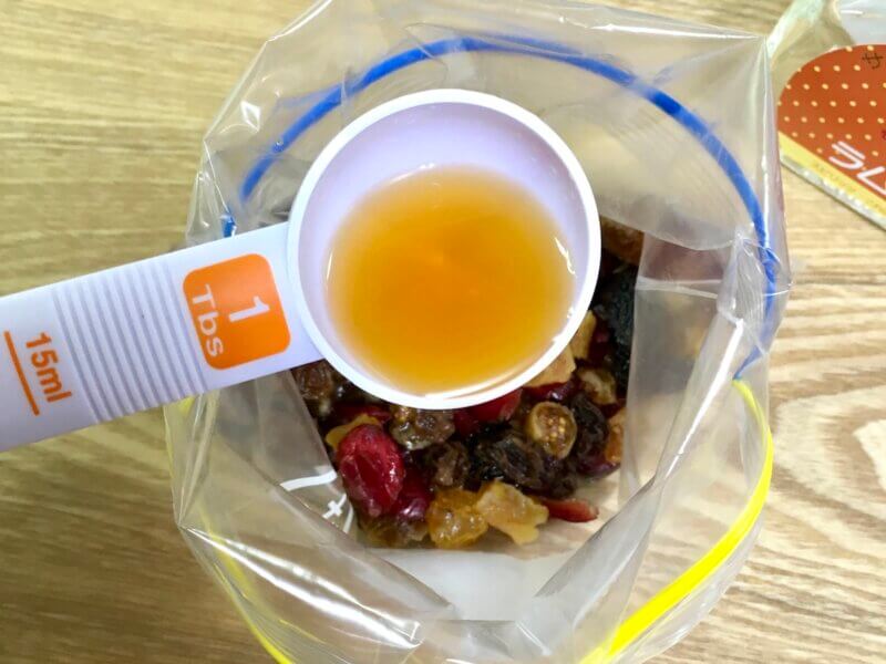 ジッパー袋に入れたドライフルーツにラム酒大さじ2を入れているところ