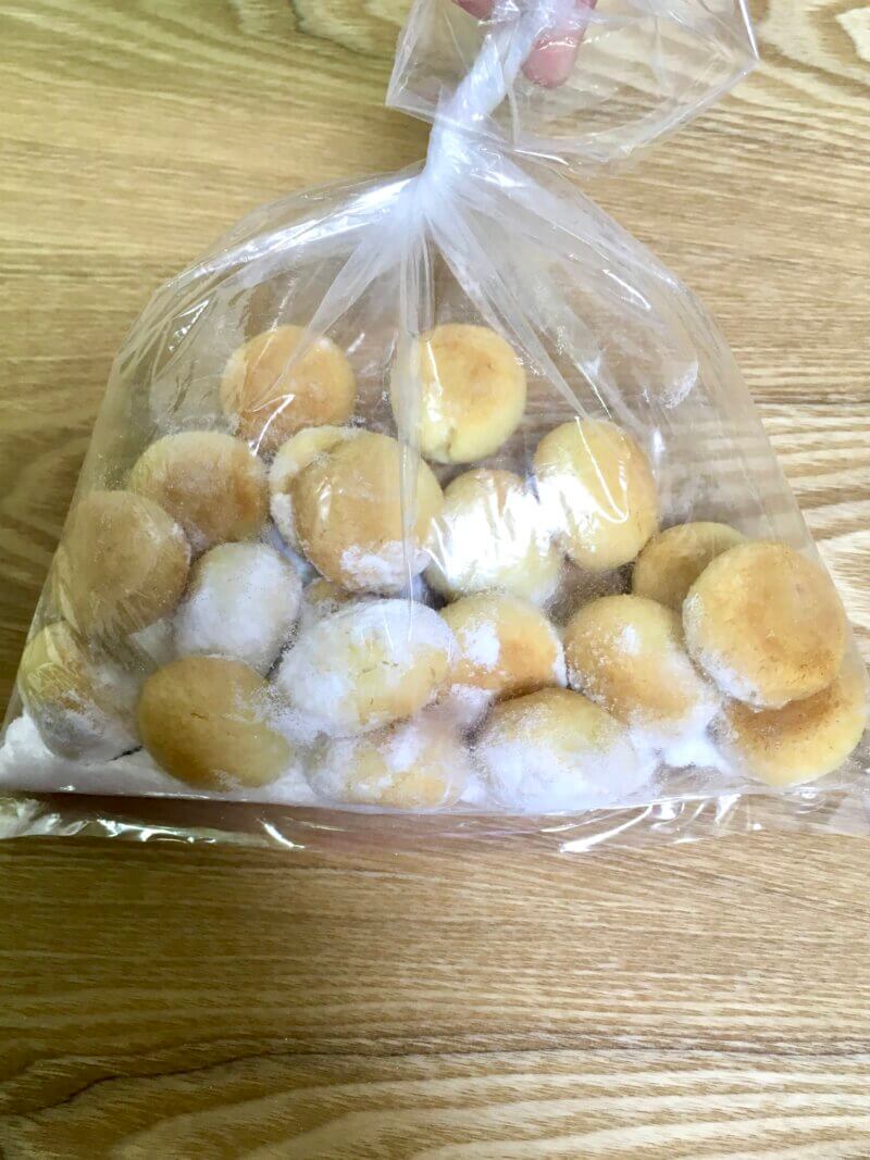 完全に冷めたスノーボールクッキーに粉砂糖大さじ2杯をまぶしているところ