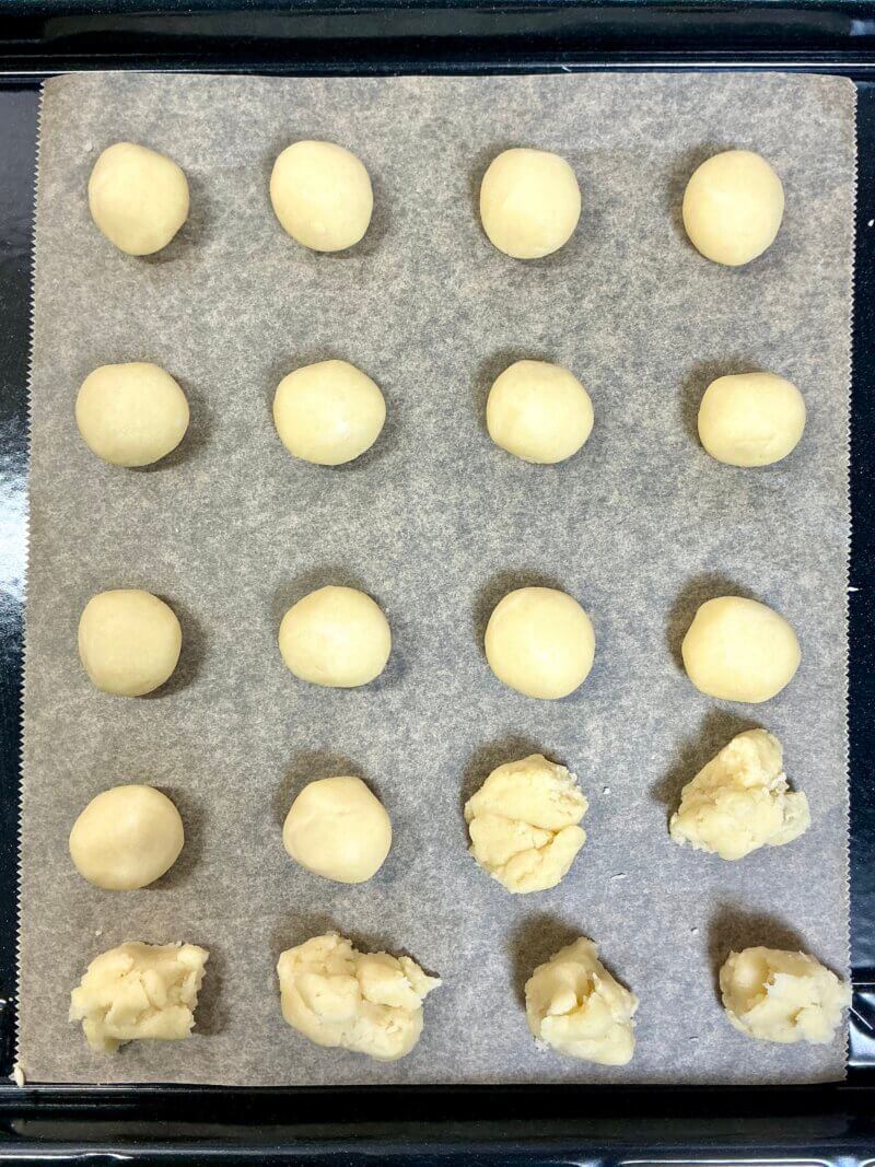 オーブン専用の天板の上にスノーボールクッキー生地を20個に分割して丸めたものを並べている様子