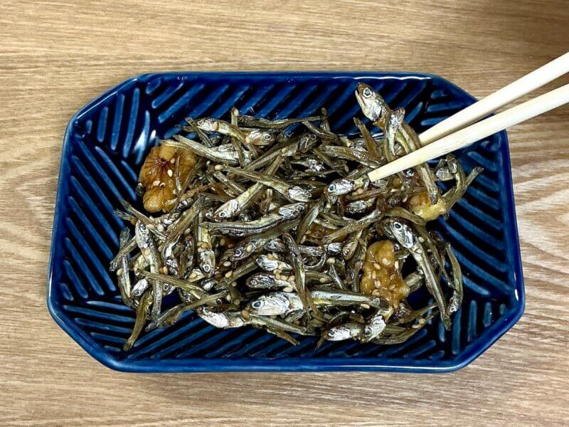 完成したごまめ(田作り)をお皿に盛り付けて箸で取っているところ