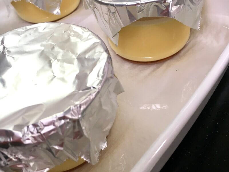 バットに並べたプリンカップの底から1cmまでお湯を注いでいる様子