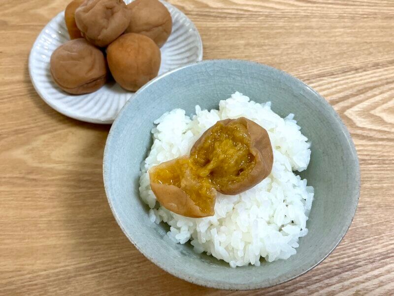 ご飯の上に乗せてカットして中身を見せている梅干しの様子